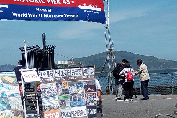 在旧金山渔人码头,退党义工布置的展板和真相伞。(韩先生提供)