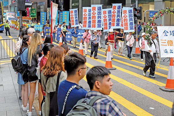 香港法轮功学员3月18日举行盛大集会游行,呼吁解体中共,结束迫害。游行队伍所经之处都有大批市民及游客观看及拍照。(李逸/大纪元)