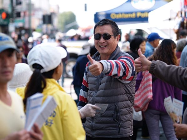 8月25日、26日,美国北加州奥克兰举行的中秋街会上,249位中国人在法轮功真相点上声明退出中共党、团、队(三退)。图为华人男士(中间)看到身穿印有“法轮大法好”字样黄色T恤衫的法轮功学员,对学员竖起敬佩的大拇指。(明慧网
