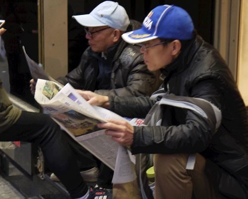 来法国旅游的大陆游客认真阅读真相报。(明慧网)
