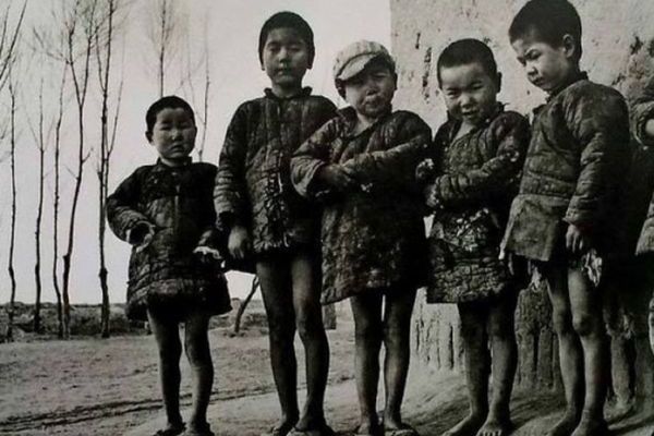 毛中国的农民生活,用饥寒交迫一词来形容实在太过苍白。图为缺裤子打赤脚的儿童,穿破棉衣晒太阳。(网络资料图片)